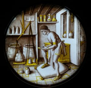 A merchant is at work in his warehouse surrounded by the tools of his trade. Standing on a woolsack, he weighs goods on a large balance using a set of standardised avoirdupois weights. The large scales are falsely balanced with ropes of different lengths, possibly a typical commentary on the theme of working for profit.The subject of this roundel has recently become clear. It is thought to represent one of the Ages of Man." -- [from the Victoria and Albert Museum. 1475-1500